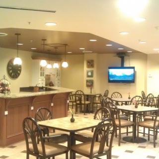 An empty cafe with a seating area, tables, chairs, a counter, and a television on the wall.