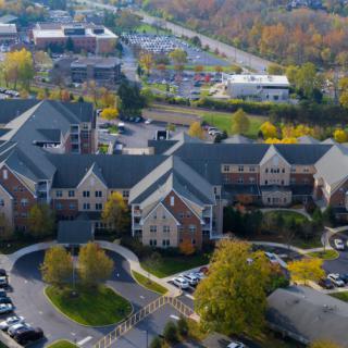 Aerial view of a residential area with parking lots and autumn trees.