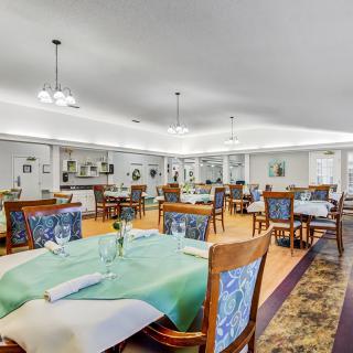A spacious dining area with neatly arranged tables and chairs under soft lighting.
