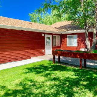 A charming red house surrounded by lush green grass on a sunny day.