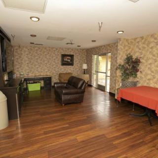 A cozy living room with wooden flooring, featuring a sofa, table, and television.