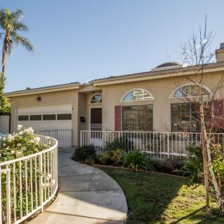 A single-story house with a curved walkway and landscaped front yard under a clear blue sky.