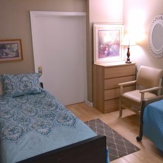 A cozy bedroom with a single bed, dresser, chair, and decorative artwork.