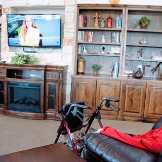 A cozy living room with a television, bookshelf, and fireplace.