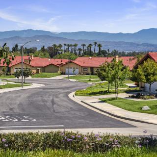 A peaceful suburban neighborhood with red-roofed houses and a mountain backdrop.