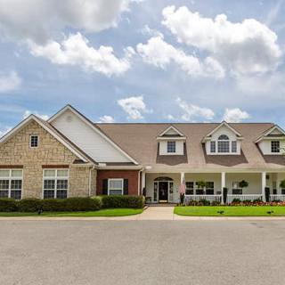 A large residential house with a well-maintained lawn under a partly cloudy sky.
