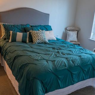 A neatly made bed with teal bedding and decorative pillows in a cozy bedroom.