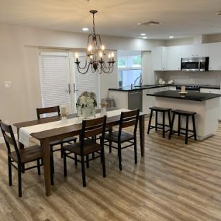 A beautifully designed open-concept dining area with modern touches, featuring a wooden dining table and chairs, complemented by a stylish chandelier.