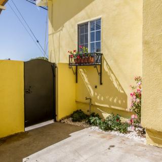 A sunny yellow house exterior with a small garden and decorative window box.