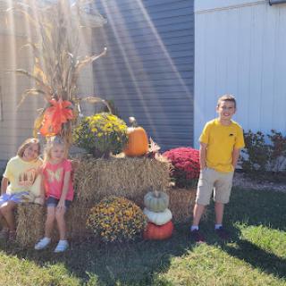 Children enjoying a sunny fall day surrounded by autumn decorations.