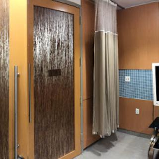 An interior view of a hospital room featuring a translucent door and a privacy curtain.