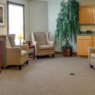A cozy waiting room with comfortable chairs, a potted plant, and soft lighting.