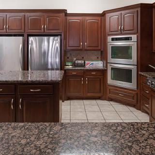 A modern kitchen with dark wood cabinets and stainless steel appliances.