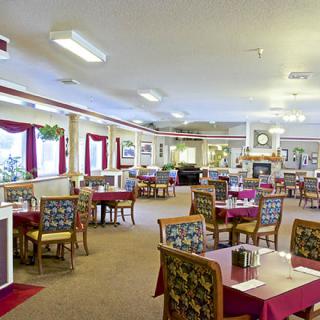 A spacious dining room with tables and chairs arranged neatly, featuring elegant decor and soft lighting.