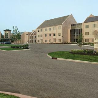 A view of a modern building complex with surrounding green spaces and a paved road.