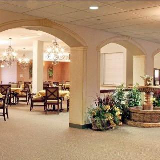 A well-decorated dining area with tables, chairs, and a central fountain surrounded by plants.