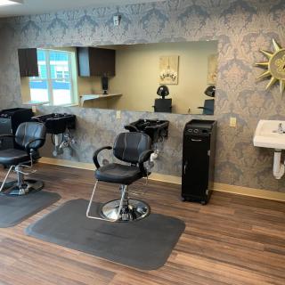 A modern hair salon with barber chairs and mirrors, featuring a wooden floor and stylish interior.