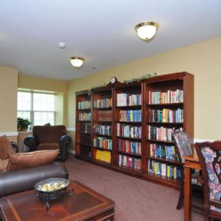 A cozy living room with bookshelves filled with books, comfortable seating, and warm lighting.