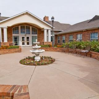 A brick building with a central entrance and a decorative fountain in the foreground.