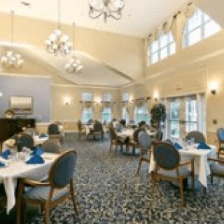 A spacious dining room with tables set and ambient lighting, featuring large windows and elegant chandeliers.