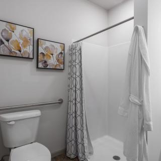 A clean and modern bathroom with decorative artwork and a white shower curtain.