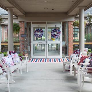 An entrance decorated with patriotic wreaths and chairs adorned with themed pillows.