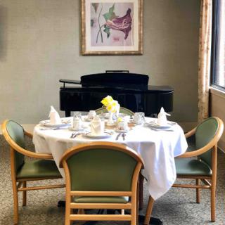 An elegantly set dining table with a piano and artwork in the background.