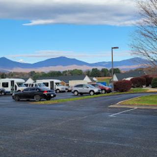 A scenic view featuring a parking lot surrounded by mountains and clear blue skies.