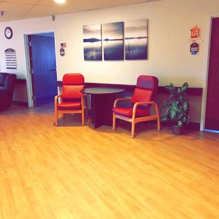 A cozy waiting area with chairs, a table, and wall art.