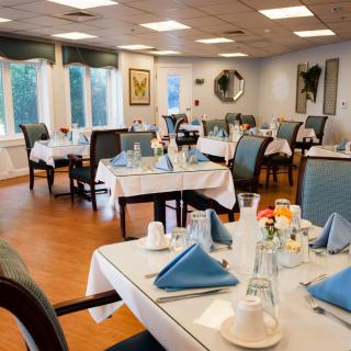 A cozy dining room with neatly set tables featuring blue napkins and a welcoming ambiance.