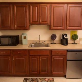 A neatly organized kitchen with wooden cabinets, a sink, microwave, and coffee maker on the countertop.