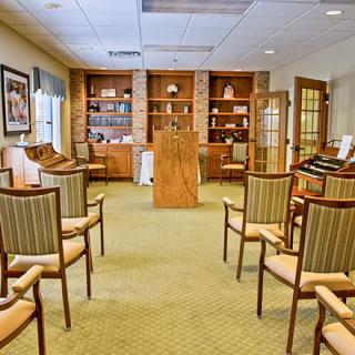 A well-organized conference room with a podium, surrounded by rows of chairs and bookshelves in the background.