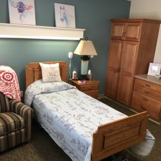 A well-decorated bedroom featuring a single bed, an armchair, and wooden furniture.