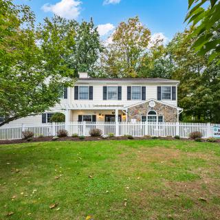 A two-story house with a spacious yard and surrounding trees.