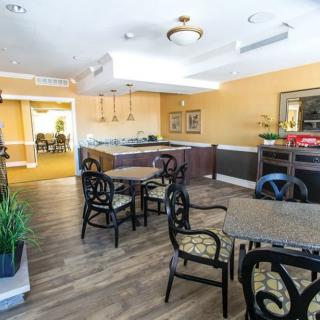 A modern dining area with tables and chairs, accented by ceiling lights and indoor plants.