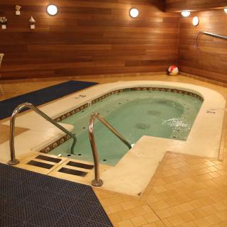 An indoor hot tub surrounded by warm wood paneling and soft lighting, creating a relaxing spa-like atmosphere.