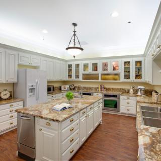 A spacious, modern kitchen with a central island and marble countertops.