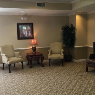 A cozy waiting area with chairs, a lamp, and a painting on the wall.