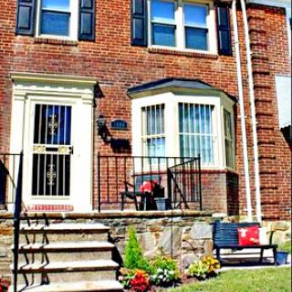 A charming brick house with a welcoming front porch and colorful flowers.