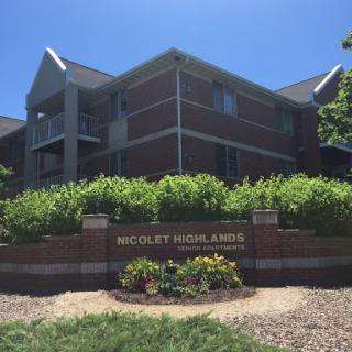 A sunny view of the residential building, Wesley Heights Apartments, surrounded by greenery.