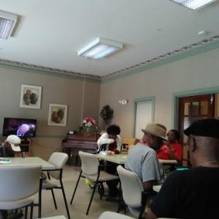 A group of people gathered in a community space, watching television together.