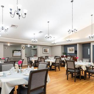 A spacious and elegantly designed dining area with multiple tables and modern chandeliers overhead.