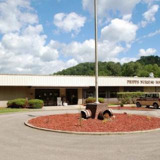 A view of a state facility surrounded by landscaped grounds under a partly cloudy sky.