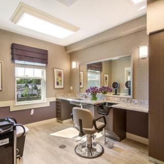 A modern salon interior with a large mirror, comfortable chair, and stylish lighting.