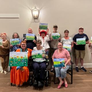Participants proudly display their artwork during a fun and creative community art class.