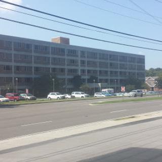 A view of a multi-story building with parked cars in front.