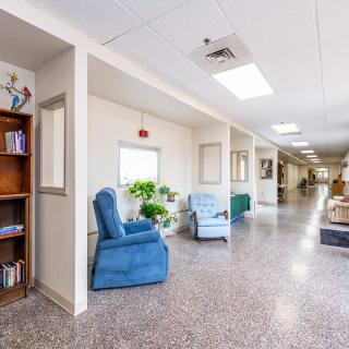 A bright and spacious hallway with comfortable seating and a bookshelf.