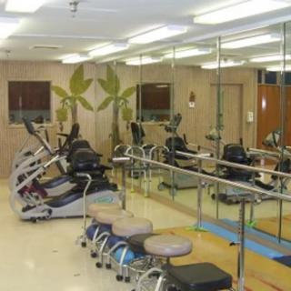 A gym with exercise equipment and mirrors lining the wall.