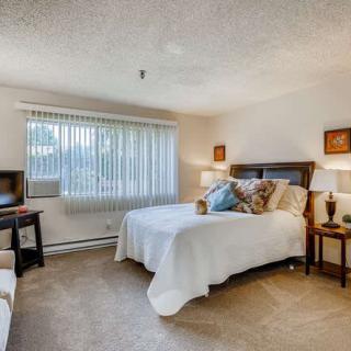 A cozy bedroom with a large window, featuring a comfortable bed and warm decor.