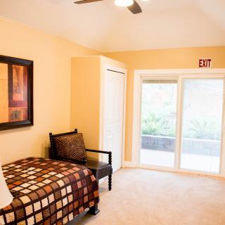 A cozy bedroom with a single bed, chair, and large window providing ample natural light.